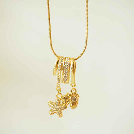Gold necklace with starfish and heart pendants on a beige background