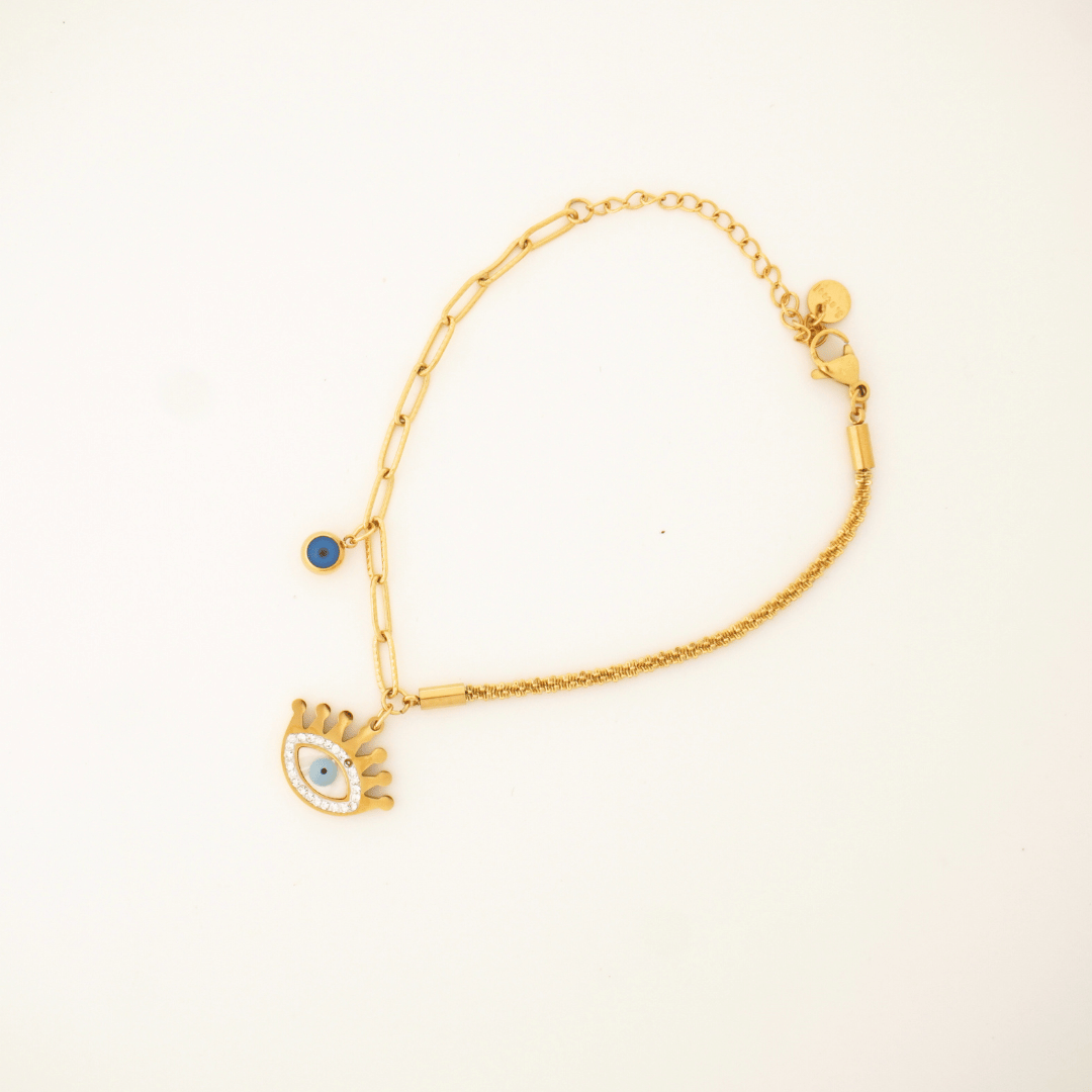 Gold bracelet with a small charm on a beige background