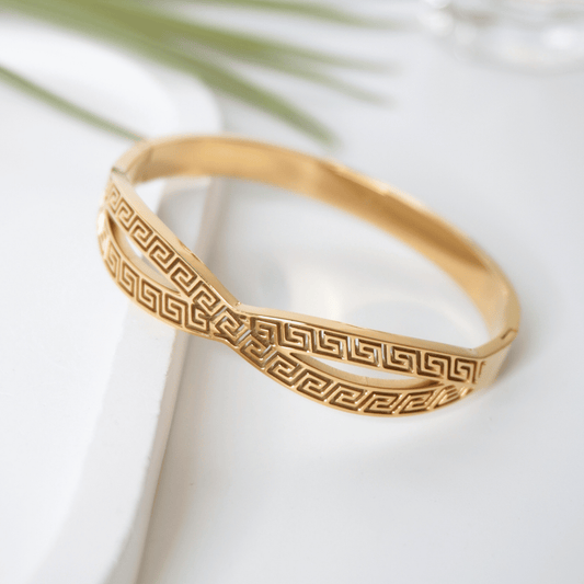 Gold bracelet with intricate pattern on a white surface