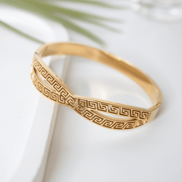 Gold bracelet with intricate pattern on a white surface