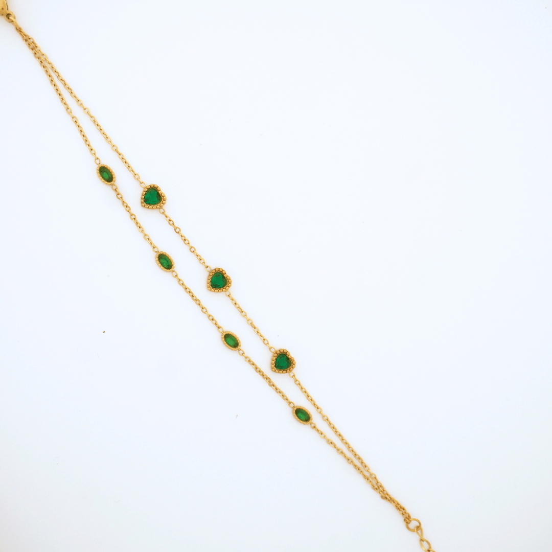 Gold bracelet with green gemstones on a white background