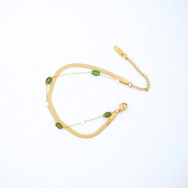 Gold bracelet with green stones on a white background
