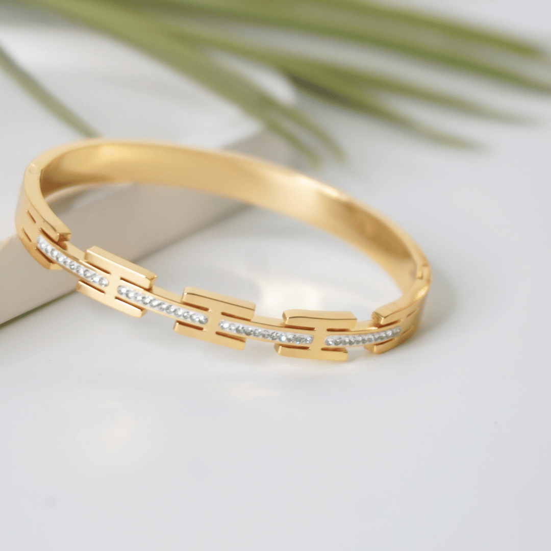 Gold bracelet with diamond accents on a light background