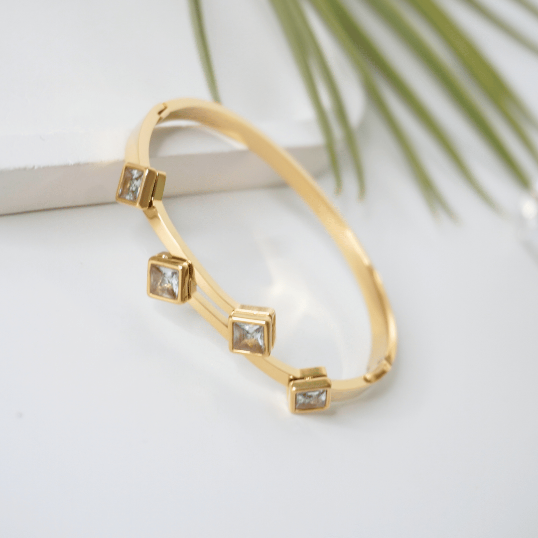 Gold bracelet with square gemstones on a light background