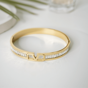 Gold bracelet with diamond accents on a light background
