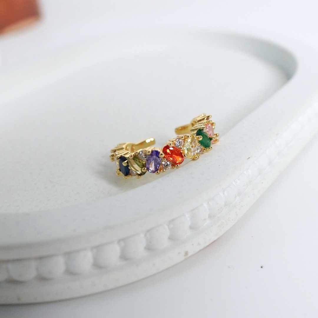 Gold earring with colorful gemstones on a white surface