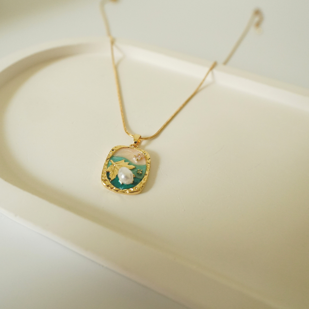 18K gold-plated necklace with a handcrafted ocean-inspired pendant featuring a pearl, leaf motif, and enamel detailing — waterproof and anti-tarnish designer jewelry.”
