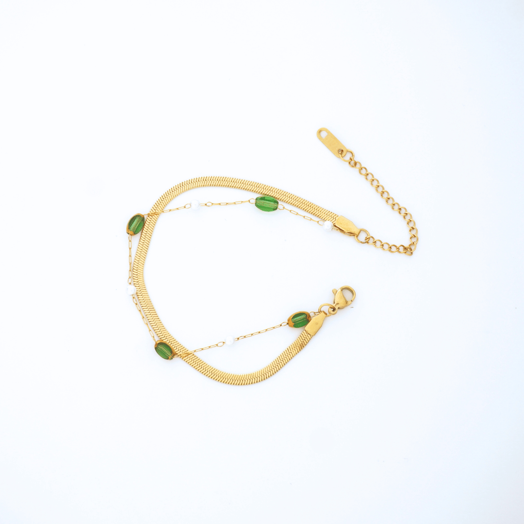 Gold bracelet with green stones on a white background