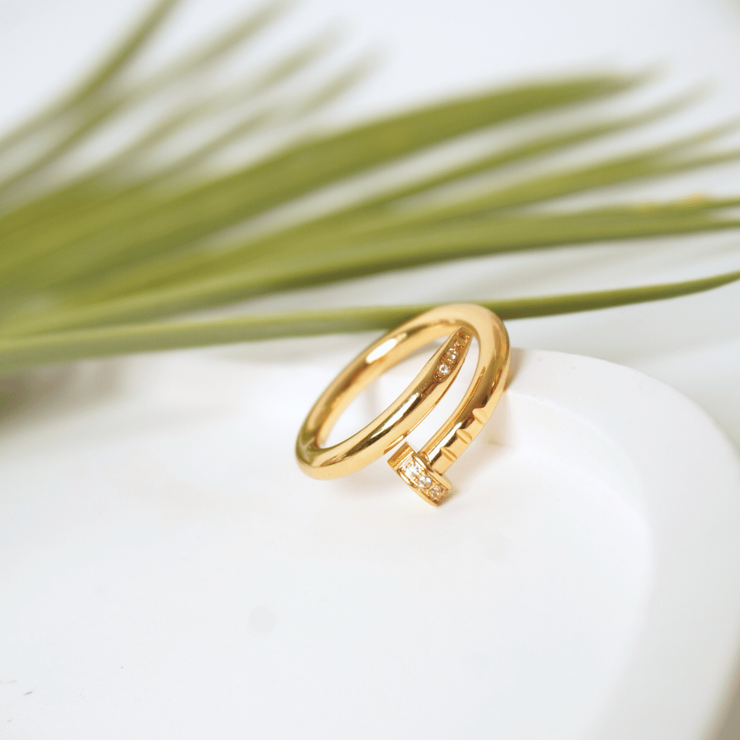 Gold ring with diamond accents on a white stone with greenery in the background