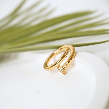 Gold ring with diamond accents on a white stone with greenery in the background