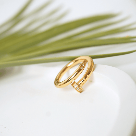 Gold ring with diamond accents on a white stone with greenery in the background