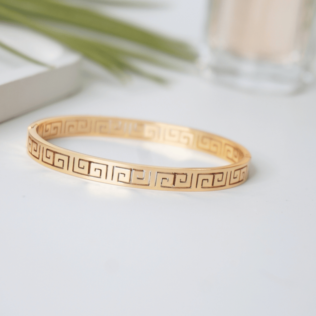 Gold bracelet with a geometric pattern on a light surface