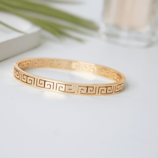 Gold bracelet with a geometric pattern on a light surface