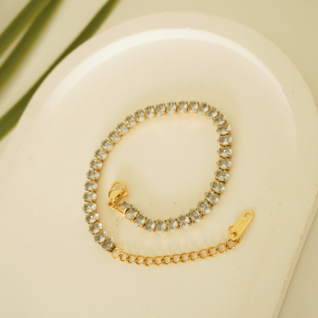 Gold bracelet with clear stones on a beige background