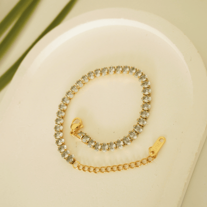 Gold bracelet with clear stones on a beige background