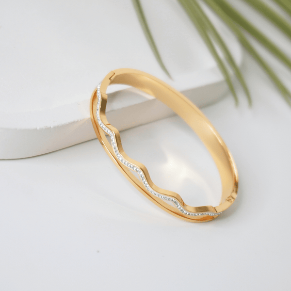 Gold bracelet with diamond accents on a white surface