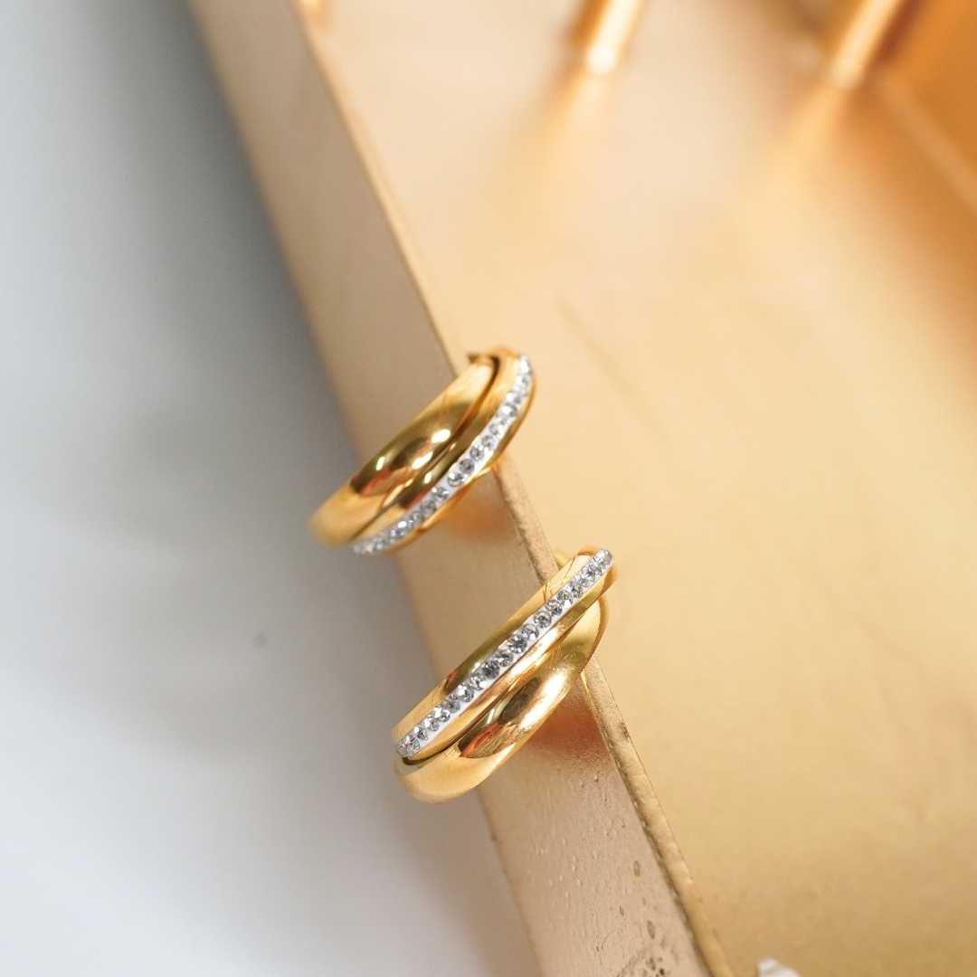 Two gold rings with diamond accents on a beige surface