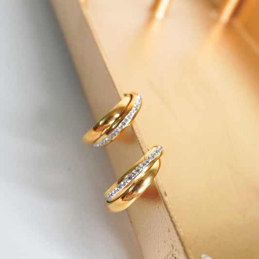 Two gold rings with diamond accents on a beige surface